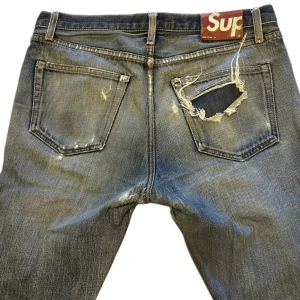 Supreme slitna blå jeans, storlek 32 - vintage blå jeans från Supreme , med riktigt feta slitningar. Jeansen har en rak passform och är gjorda i denim. waist 32 längd 34
