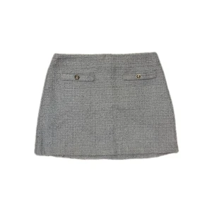 Grå blå kortkjol i bouclé från H&M - Stilren grå/blå kortkjol från H&M i bouclé-liknande tyg med två dekorativa fickor framtill och knappar. Kjolen har en rak passform och dragkedja bak. Perfekt för dig som gillar klassisk och trendig stil.