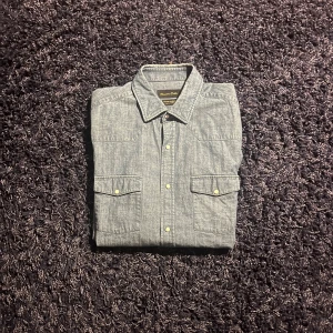 Blå skjorta från Massimo Dutti - Snygg blå skjorta från Massimo Dutti i storlek L. Skjortan har klassisk krage, två bröstfickor med lock och tryckknappar framtill. Tillverkad i ett mjukt bomullstyg som ger en avslappnad men stilren look.