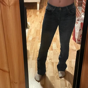 Mörkblå bootcut jeans - Snygga mörkblå jeans med bootcut passform och klassisk femficksdesign. Jeansen har en normal midja och är tillverkade i stretchigt denim för skön passform. Perfekta för dig som gillar en tidlös look med lite utsvängda ben.