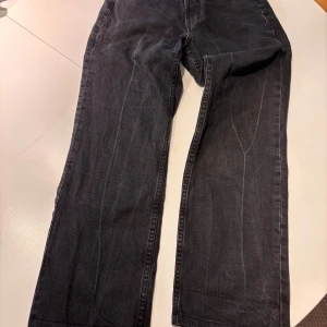 Svarta raka jeans high waist - Svarta jeans med rak passform och hög midja. Jeansen har en klassisk femficksdesign och är tillverkade i denim. Snygg, enkel stil som passar till det mesta och har en slim straight siluett.