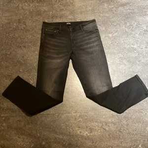 Svarta slim jeans Jack & Jones Glenn - Svarta jeans från Jack & Jones i modellen Glenn med slim fit. Klassisk femficksdesign, diskret tvättad look och smal passform. Tillverkade i stretchig bomullsblandning för extra komfort. Perfekta för dig som gillar en stilren och modern vibe.