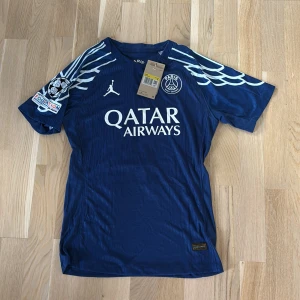 Psg tröja player edition  - Nypris 1800kr mitt pris 999kr Blå PSG x Jordan fotbollströja med vita detaljer och tryck, korta ärmar och Dri-Fit ADV-material. Nummer 14 och D. Doué på ryggen, Champions League-patch på ärmen och Qatar Airways som sponsor framtill. Snygga vinge-mönster på axlarna.