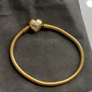 Pandora armband guld - Super fint Pandora armband, storlek 17 (17cm). Har tappat lite färg på låset, men annars väldigt bra skick. Köpte det av en annan tjej som säger att det är äkta, men kan inte garantera. (Har bild på kvittot som jag fick av henne) skriv privat för frågor och bilder!💗💗/säljer då det inte kommer till användning!