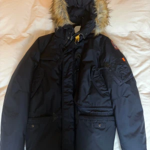 Mörkblå dunjacka från Parajumpers - Säljer en Parajumpers Right Hand Eco i mörkblå, storlek Young Large (motsvarar ca XS). Jackan är i mycket bra skick, varm och snygg med många praktiska fickor. Huvan har avtagbar päls.  Kommer med både QR-kod och authenticator som bevis på äkthet.   Nypris: ca 10 000 kr Pris: 2 500 kr  Perfekt för dig som vill ha en stilren, funktionell och äkta Parajumpers-jacka! 