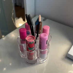 Sminkställ i akryl med flera fack - Snyggt och praktiskt sminkställ i genomskinlig akryl med sju cylindriska fack, perfekt för att organisera läppbalsam, mascaror, ögonbrynspennor och andra sminkfavoriter. Passar perfekt på sminkbordet för att hålla ordning på dina produkter.