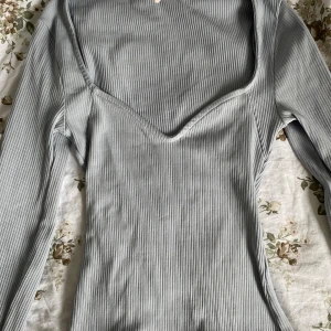 Ljusgrå ribbad långärmad topp - Snygg ljusgrå ribbad topp med lång ärm och v-ringad. Endast använd en gång💕