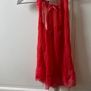 Röd kort klänning/ nattlinne Malizia by La Perla - Superfin röd kort klänning/nattlinne från Malizia by La Perla med tunna axelband som knyts i nacken, transparent tyg och spetsdetaljer längst ner. Klänningen är ärmlös och har en lätt volangkant. Perfekt för dig som vill sticka ut med en feminin och luftig look. I 95% silkes!😍😍