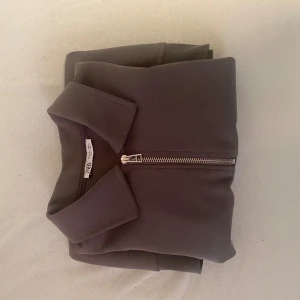 Brun half zip tröja från Zara - Säljer en brun långärmad tröja från Zara med krage och snygg half zip-dragkedja framtill. Tröjan har en clean och stilren look, perfekt för lager-på-lager och chill vardagsstil. Mjuk och skön i materialet, passar till det mesta.