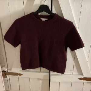 Vinröd stickad topp från Gina Tricot - Säljer en vinröd stickad topp från Gina Tricot i storlek 146/152. Toppen har korta ärmar. 