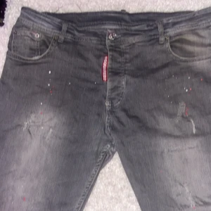 Grå Dsquared2 jeans  - Snygga grå jeans från Dsquared2 med slitna detaljer och diskreta färgstänk. Klassisk femficksmodell med smal passform och låg midja. Perfekta för dig som gillar en edgy streetstil och vill sticka ut lite extra.