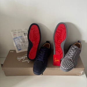 Christian Louboutin sneakers med röd sula - Säljer två par exklusiva Christian Louboutin sneakers. Ena paret är mörkblå mocka med klassisk röd sula och snörning. Det andra paret är grå mocka med silverfärgade nitar på tån, röd sula och snörning. Båda paren har rund tå och lyxig känsla. Båda skorna är helt nya alldrig använda. Säljer båda för 2800kr. 1500kr för en sko. Dom blåa är storlek 42 och dom gråa är storlek 43