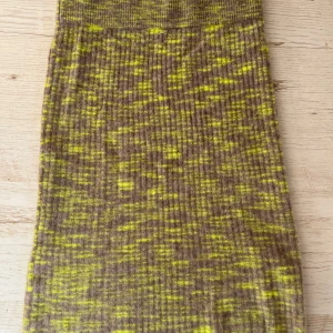 Stickad alpacka  kjol från J.Lindeberg i beige och gul - Stickad långkjol från J.Lindeberg i en mix av beige och gul med melerat mönster. Kjolen är ribbad och har en mjuk, fluffig känsla tack vare materialblandningen med alpacka och ull. Perfekt för dig som gillar unika färgkombinationer och vill ha något riktigt cozy.