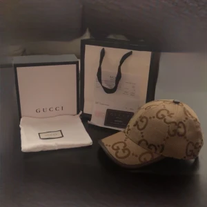 Gucci keps jumbo  - Säljer en exklusiv keps från Gucci i beige och brunt med det klassiska GG-monogrammet över hela kepsen. Kepsen har böjd skärm och är tillverkad i canvas med detaljer i brunt. Perfekt för dig som vill sticka ut med en lyxig accessoar.