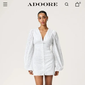 Vit Florence Dress från Adoore - Supersöt vit kortklänning från Adoore helt oanvänd med alla lappar kvar. Puffiga långärmar, djup v-ringning och knappar framtill. Klänningen har broderade blommor i tyget och markerad midja. Säljer då den ej kom till användning som jag tänkte. Nypris på klänning är 1495. Priser kan absolut diskuteras vid högt intresse och snabba affär☺️