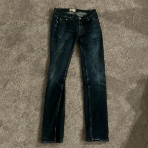 Mörkblå jeans från Acne Studios - Snygga mörkblå jeans från Acne Studios med klassisk femficksdesign och raka ben. Jeansen har coola slitningar och kontrastsömmar, vilket ger en trendig look. Perfekta för dig som gillar stilrena och moderna jeans. 30/32