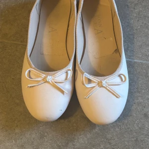 ljusrosa ballerinaskor med rosett - Säljer ett par klassiska ljusrosa ballerinaskor med rund tå och söt rosettdetalj framtill. Skorna har en platt sula och är perfekta för dig som gillar en enkel och stilren look. Materialet är syntet och de är lätta att matcha till olika outfits.