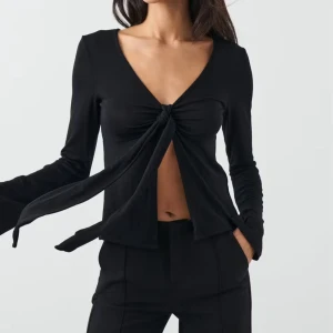 Svart topp med knyt - Svart topp från Gina Tricot med lång ärm och djup v-ringning. Priset går att diskutera💕