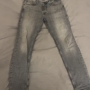 Grå tapered jeans från Jack & Jones - Snygga grå jeans från Jack & Jones i modellen Tapered Mike. Jeansen har en tvättad look med ljusare partier och klassiska fem fickor. Passformen är tapered och normal midja. Perfekta för dig som gillar en modern och avslappnad stil. Priset är inte hugget i sten vid snabbaffär!