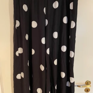 Svarta prickiga wide byxor från SHEIN - Säljer ett par svarta byxor från SHEIN Curve i storlek 2XL med stora vita prickar. Byxorna har en loose och wide passform med resår i midjan och är tillverkade i ett lätt och luftigt syntetmaterial. Perfekta för dig som gillar statement-plagg och vill sticka ut.