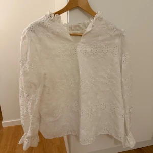 Blus - Vit blus med mönster och volang vid handleden