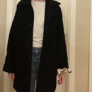 Svart kappa med knappar - Säljer en svart kapp med oversized passform och stora knappar framtill. Den är lite nopprig, men sen är även materialet ”grövre” och ska därmed vara så! Perfekt nu till höst 🍂 