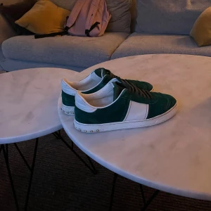 Valentino flycrew  - Byte!!!!!Snygga Valentino flycrew sneakers i grön mocka och vit skinn med coola nitar runt sulan. Klassisk låg modell med snörning och rund tå. Perfekt för dig som vill sticka ut med exklusiva detaljer och lyxig känsla.