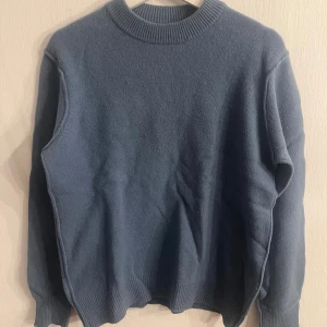 Blå stickad tröja från Samsøe Samsøe - Blå ull tröja från Samsøe Samsøe med rund halsringning och ribbade muddar. Perfekt för lager-på-lager under kyliga dagar. Enkel och stilren design som funkar till allt. Snygg passform och skön känsla. 95% ull, 5% Kashmir. 