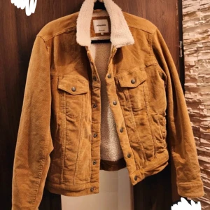 Brun manchesterjacka med teddykrage - Säljer en brun manchesterjacka från JACK & JONES med vit teddykrage och foder. Jackan har klassisk jeansjacke-look med knappar framtill, två bröstfickor med lock och sidofickor. Perfekt för höst och vinter, riktigt snygg och chill stil.