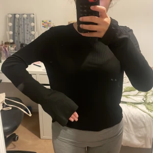 Svart långärmad topp från Nelly - En svart långärmad topp från Nelly i ribbat material. Modellen är enkel med rund halsringning och långa ärmar, perfekt att styla med jeans eller kjol. Tunn och stretchig, vilket gör den riktigt skön att bära.