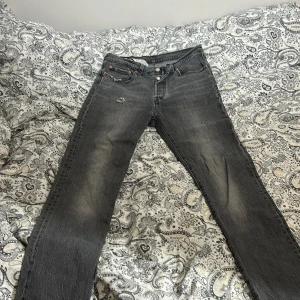 Levi's 501 grå jeans W27 L30 - Säljer ett par grå Levi's 501 jeans med klassisk femficksdesign och knäppning fram. Jeansen har en rak passform och slitna detaljer på framsidan för en cool, vintage look. Perfekta till sneakers eller boots. Dom har slitningar och den på höger ben är rätt igenom så man vet det🤩 säljer billigt 