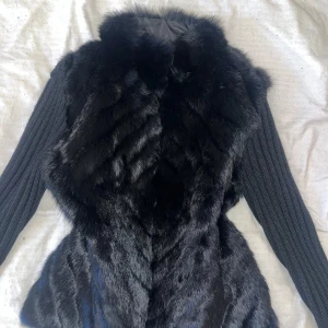 Svart pälsväst med ribbade ärmar - Snygg svart pälsväst med långa ärmar. Köpt för 700kr second hand. Skulle gissa på att det är äkta päls.