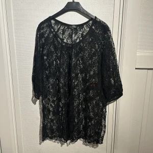 Svart spetsblus från Chic - Säljer en elegant svart spetsblus från Chic. Blusen har trekvartsärmar och ett vackert spetsmönster som ger en stilren look. Perfekt för att lägga till en touch av elegans till din garderob.