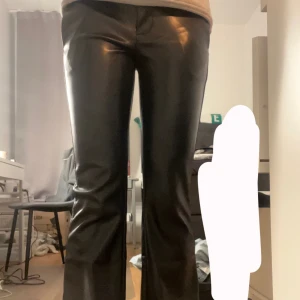 Svarta bootcut skinnbyxor - Snygga svarta skinnbyxor med en glansig finish. Byxorna har en bootcut-stil som ger en trendig look. De är helt nya med lappen kvar och endast testade 💞 Skriv vid frågor eller funderingar!