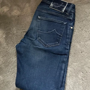 Mörkblå jeans från Jacob Cohen - Snygga mörkblå jeans från Jacob Cohen med klassisk femficksdesign och subtila slitningar. Jeansen har en normal passform och är tillverkade i högkvalitativt denim. längd: 96cm 173cm på bilden
