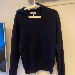 Mörkblå tröja från & Other Stories - Säljer en stilren mörkblå tröja från & Other Stories. Tröjan har en v-ringad design och långa ärmar, perfekt för en elegant och avslappnad look. Passar bra till både jeans och kjol. Perfekt för kyligare dagar!