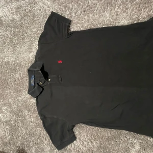 Svart ralp Lauren pique  - Stil ren raffe pique som är i ett fint sick med en snygg syd röd ralp Lauren logga på bröstet perfekt för sommaren.passar folk i storlek s