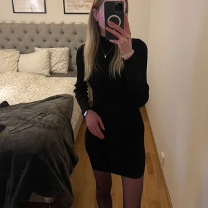 Svart ribbad klänning - Snygg svart ribbad klänning med lång ärm och hög krage. Stretchig