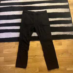 Svarta byxor från Tommy Hilfiger - Snygga svarta byxor från Tommy Hilfiger med klassisk design. De har en knapp och dragkedja framtill och är perfekta för en stilren look. Passar bra till både vardag och mer uppklädda tillfällen. Riktigt fina knappt använda. 
