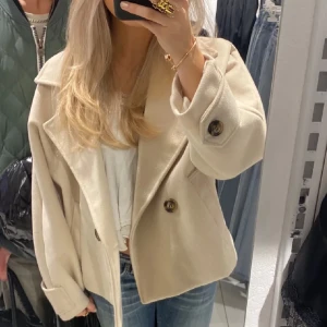 Kappa kort - Snygg beige kappa med stora knappar och bred krage. Perfekt för kyliga dagar med sin stilrena design. Passar bra till jeans och andra casual outfits. Den är från Missay. Skulle säga att storleken är ett xs/s. Priset kan alltid diskuteras🩷