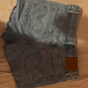 Blå jeansshorts från Levi's - Säljer ett par klassiska blå jeansshorts från Levi's med fransiga kanter och knappar. Köpte de för 900 kr och har använts 2 gånger. Pris kan diskuteras💕