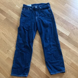 Blå loose fit jeans från H&M - Säljer ett par blå loose fit jeans från H&M. De har en klassisk femficksdesign och är tillverkade i ett bekvämt denimtyg. Perfekta för en avslappnad stil.