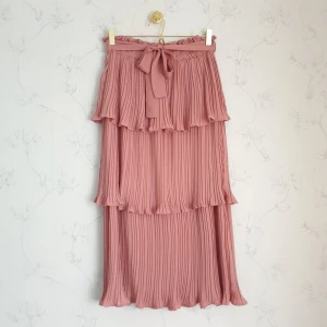 Romantisk rosa volangkjol - 🌹FÖRST TILL KVARN!🌹En romantisk rosa plisserad midikjol med volanger. Kjolen har tre lager av volanger och kommer med ett band till midjan,har ett elastiskt band. Från Ginatricot. Helt slutsåld på hemsidan, använd endast få antal gånger i nyskick