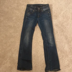 Blå jeans från G-Star Raw - Snygga blå jeans från G-Star raw mod bootcut med jättesnygga detaljer i jättebra skick. Använd några gånger.  23 i midja och 28 i längd. Vanligt pris 1300 