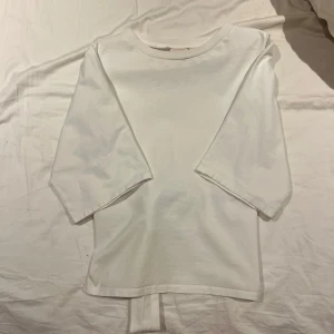 Vit topp från Nelly - Säljer en stilren vit topp från Nelly med knytning i ryggen. Perfekt för en avslappnad look. Toppen är i mjukt material och har en enkel design som passar till mycket. Endast använd tre gånger.