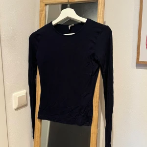 Marinblå långärmad tröja - Säljer en marinblå långärmad tröja. Tröjan är i ett mjukt material och har en rund halsringning. Den är i strl S från Nelly. Sparsamt använd och i väldigt fint skick trots lite nopprig på högra armen som framkommer på bilderna✨