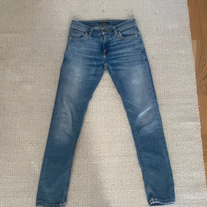 Blå jeans från Nudie Jeans - Snygga blå Nudie Jeans. Sitter slim och passar bra till nästan allt. Bra skick men finns tecken på användning nere vid hälarna. Kan sänka pris vid snabb affär 