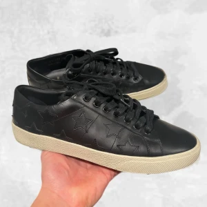 Saint Laurent skor svarta - Skohylla rensning. •Saint Laurent SL/01 sneakers stars svarta. Skick: 9/10, ända är en liten lagning som gjorts av skomakare på cap toe’n på vänster sko, inge märkvärdigt! (Se bild 3).  mycket fint skick, nästintill aldrig använda! Storlek: 39 1/2, YSL är stora i storlek. Dvs sitter mer som 40 - liten 41! Nypris: 7 000 kr~. Köpt ifrån Trendsellers. Givetvis äkta såklart✅ Bara skorna medföljer! Hör av dig vid frågor eller funderingar, mvh Oliver;)