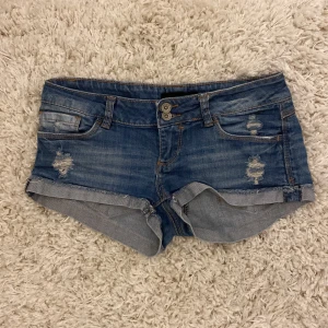 Blå jeansshorts  - Säljer ett par snygga blå jeansshorts från Tally Weijl. De har en lågmidjad passform med slitna detaljer och uppvikta kanter. Jag köpte av en annan tjej men de passade tyvärr inte. 