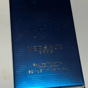 Versace Eros Eau de Toilette 50 ml - Säljer en Versace Eros Eau de Toilette i en elegant blå förpackning med guldtext. Flaskan innehåller 50 ml av denna ikoniska doft som kombinerar friska och maskulina noter. Perfekt för den som vill ha en tidlös och kraftfull parfym.